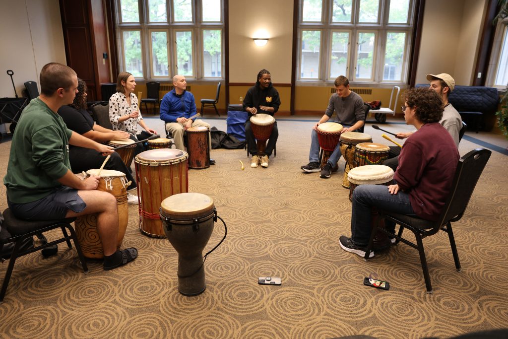 Sipho Ngcamu and a group of seven percussion students at Mizzou sit in a drum circle.