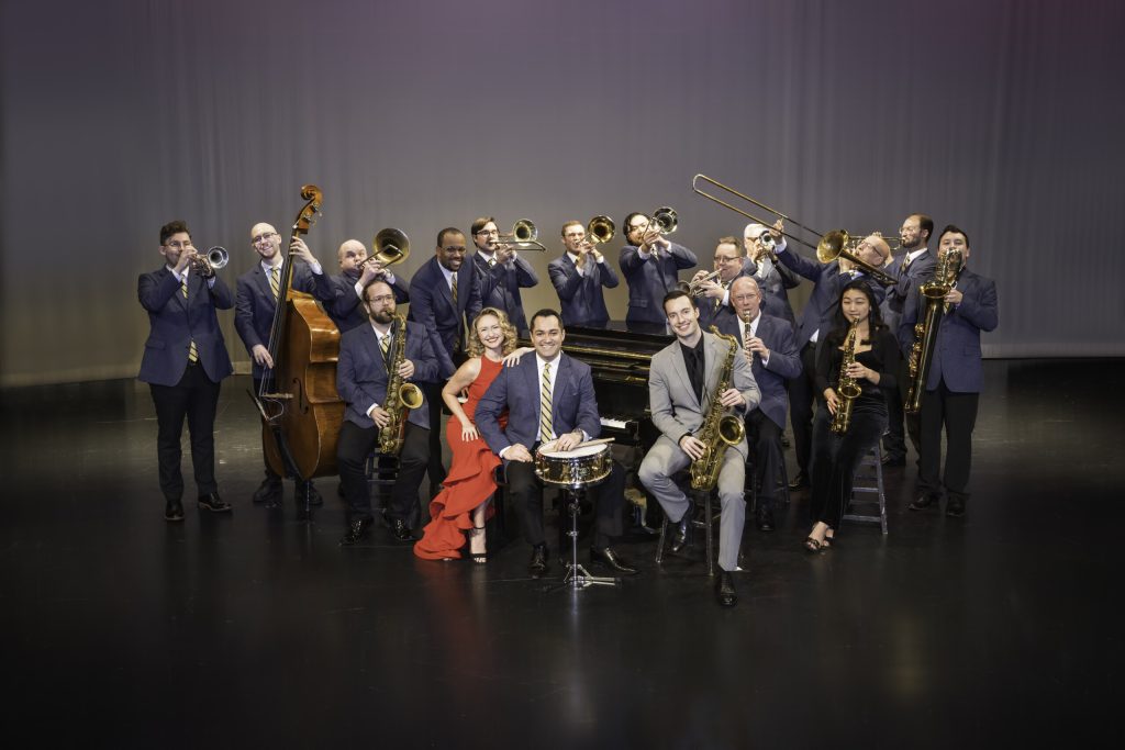 Glenn Miller Band pose on stage with their instruments. 